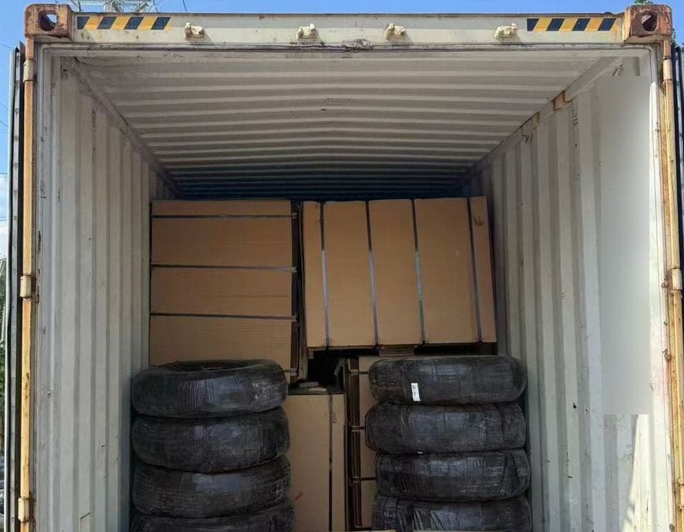 A container loaded with strapped flat stacks at the back and rounded bundles standing on the floor in front