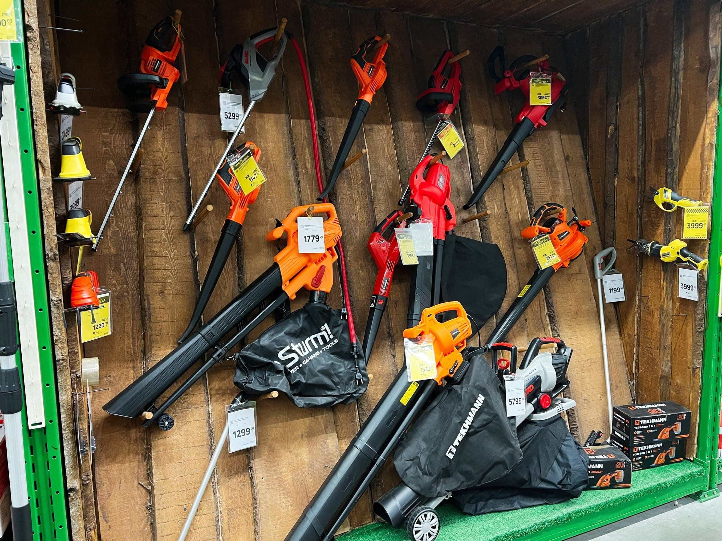 Leaf blowers and garden trimmers hanging on a shop wall